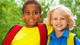 Bilde av to gutter som står skulder ved skulder og smiler