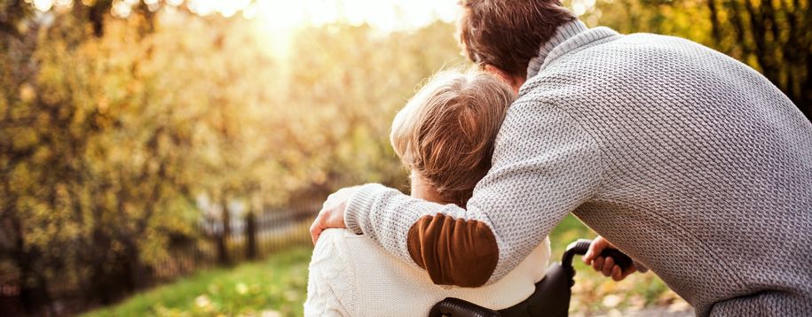 Kvinne i rullestol og mann som står ved siden av, som holder rundt hverandre